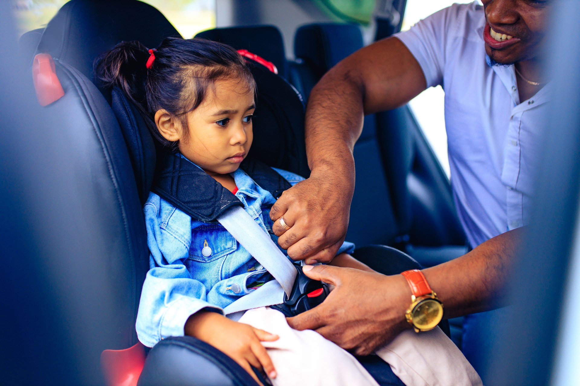 latin hispanic man fasten his baby in car seat