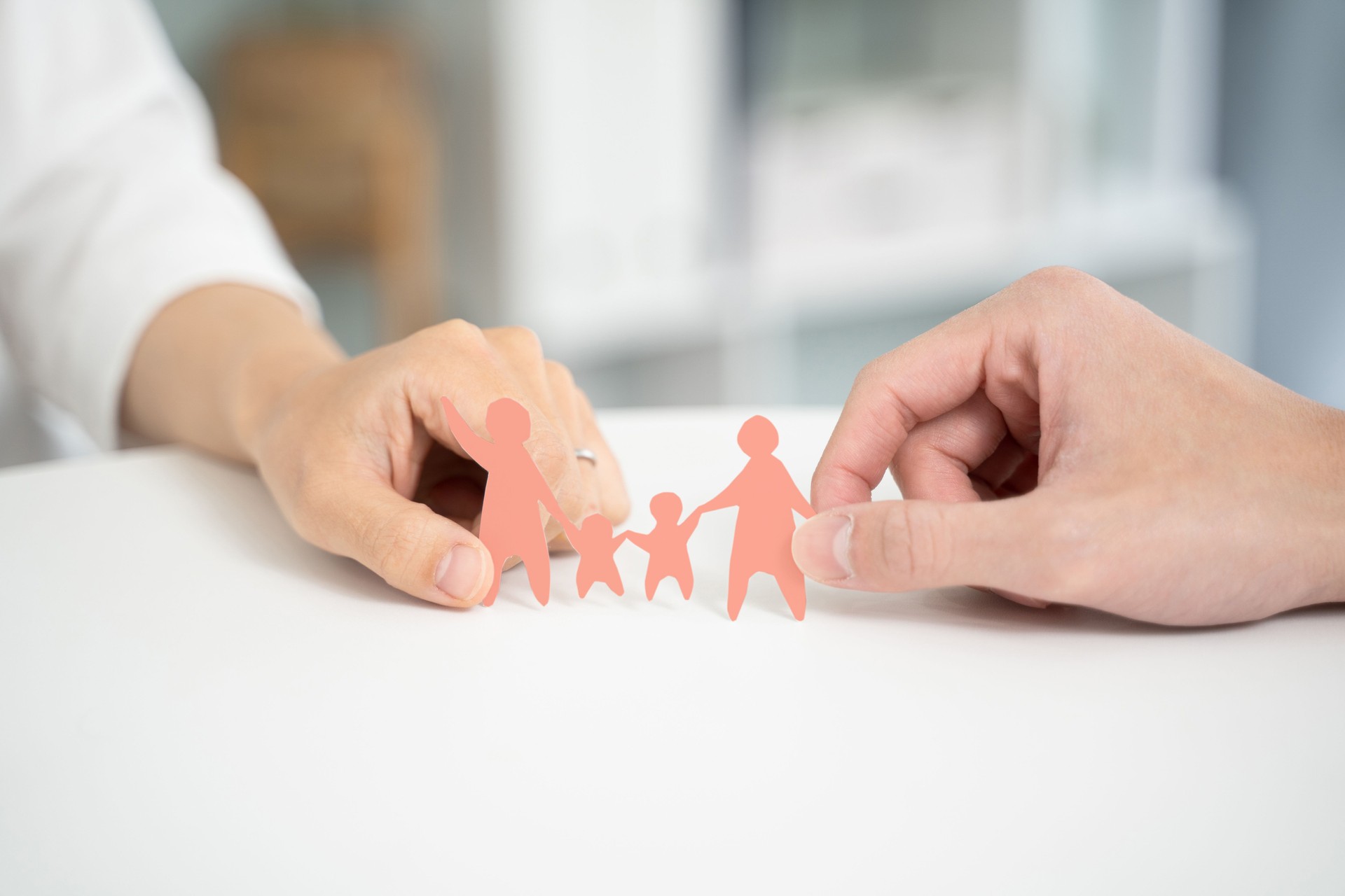 Hands of a couple working together and holding a paper cutout of their family.