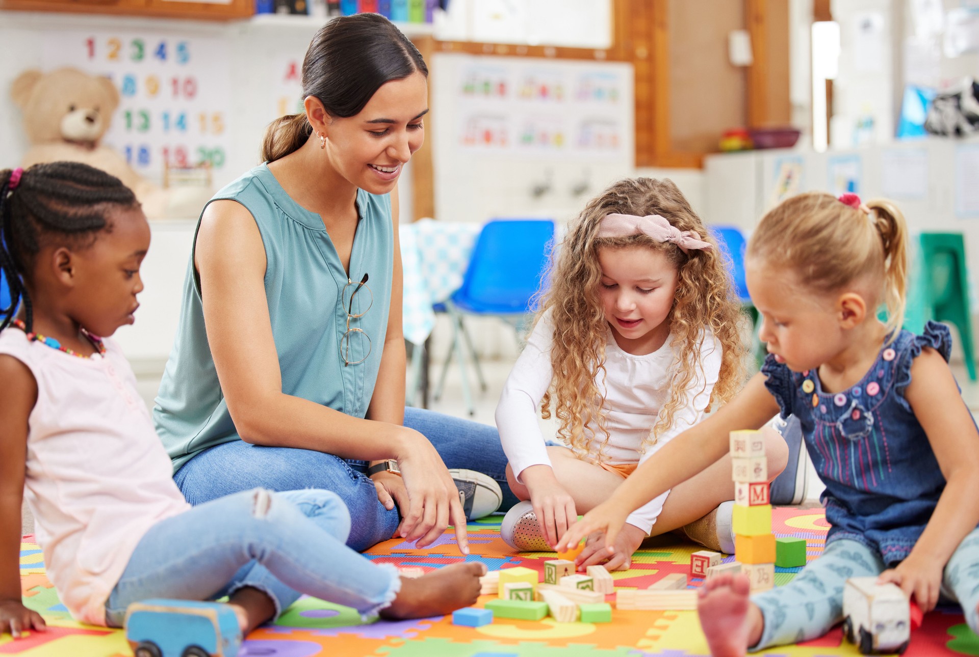 Toys, teacher and woman with education, students or ideas with conversation, lessons or teaching. Person, educator or children building, knowledge or kids in a classroom with kindergarten or learning