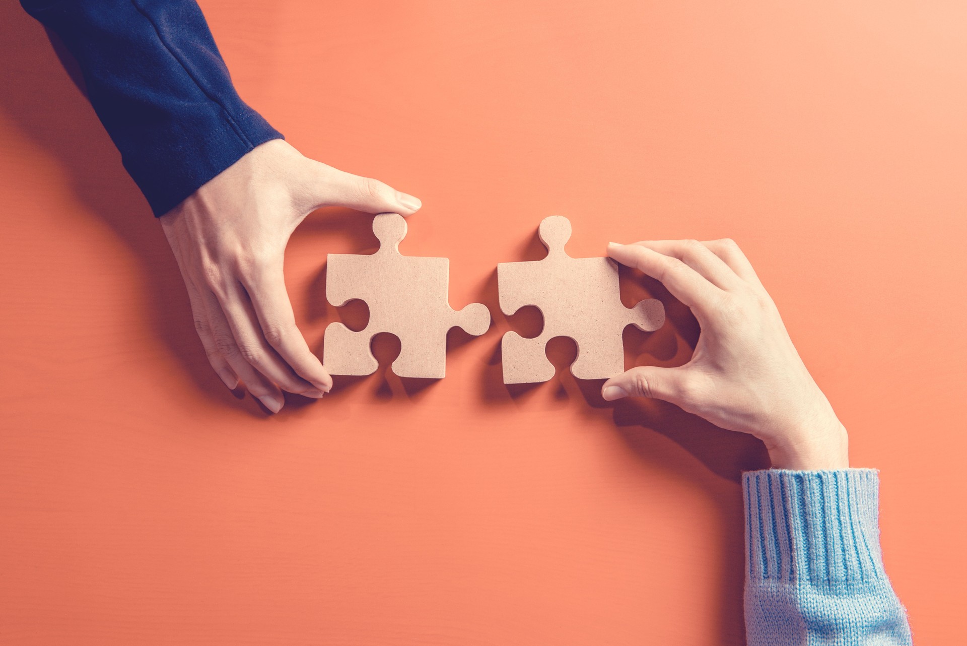Two hands holding jigsaw, Concept for teamwork Building a success.